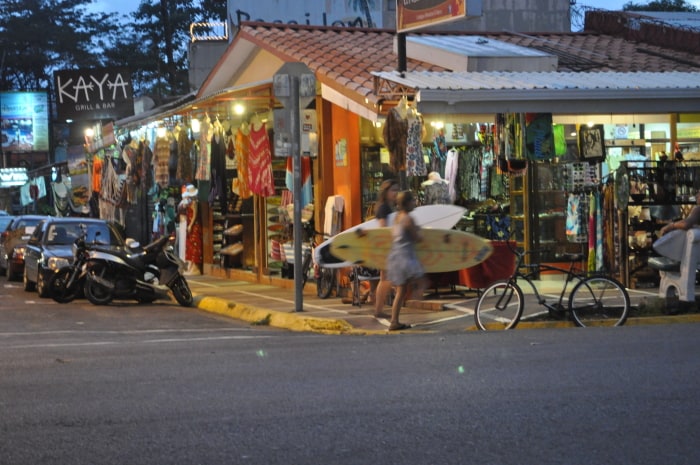 A bustling street in Jaco with shops and restaurants.